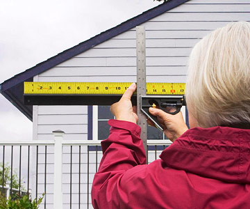 Measuring roof pitch from the ground by holding a framing square against the gable end