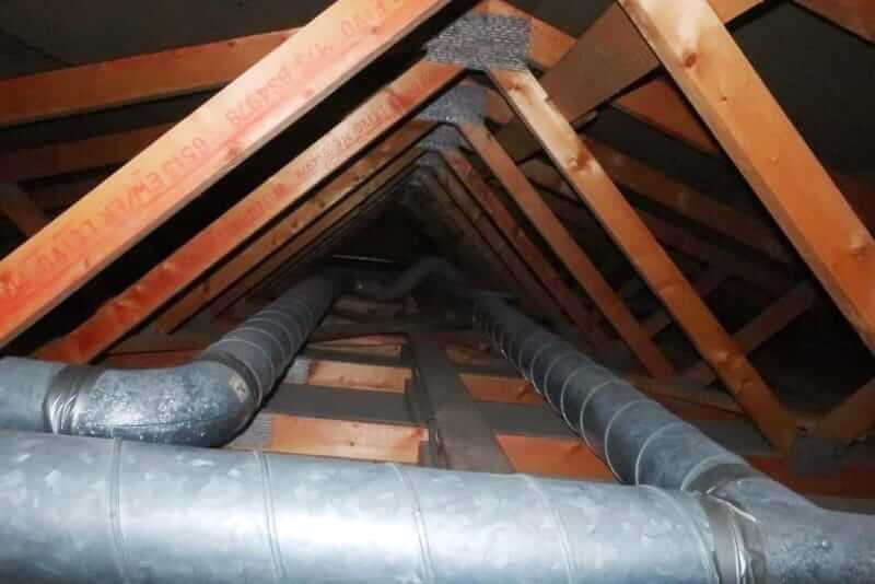 Bare sheet metal heating ducts running across an unfinished attic floor