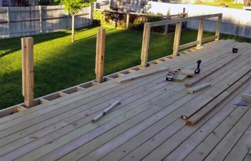 Wood deck railing with evenly spaced posts along the open edge